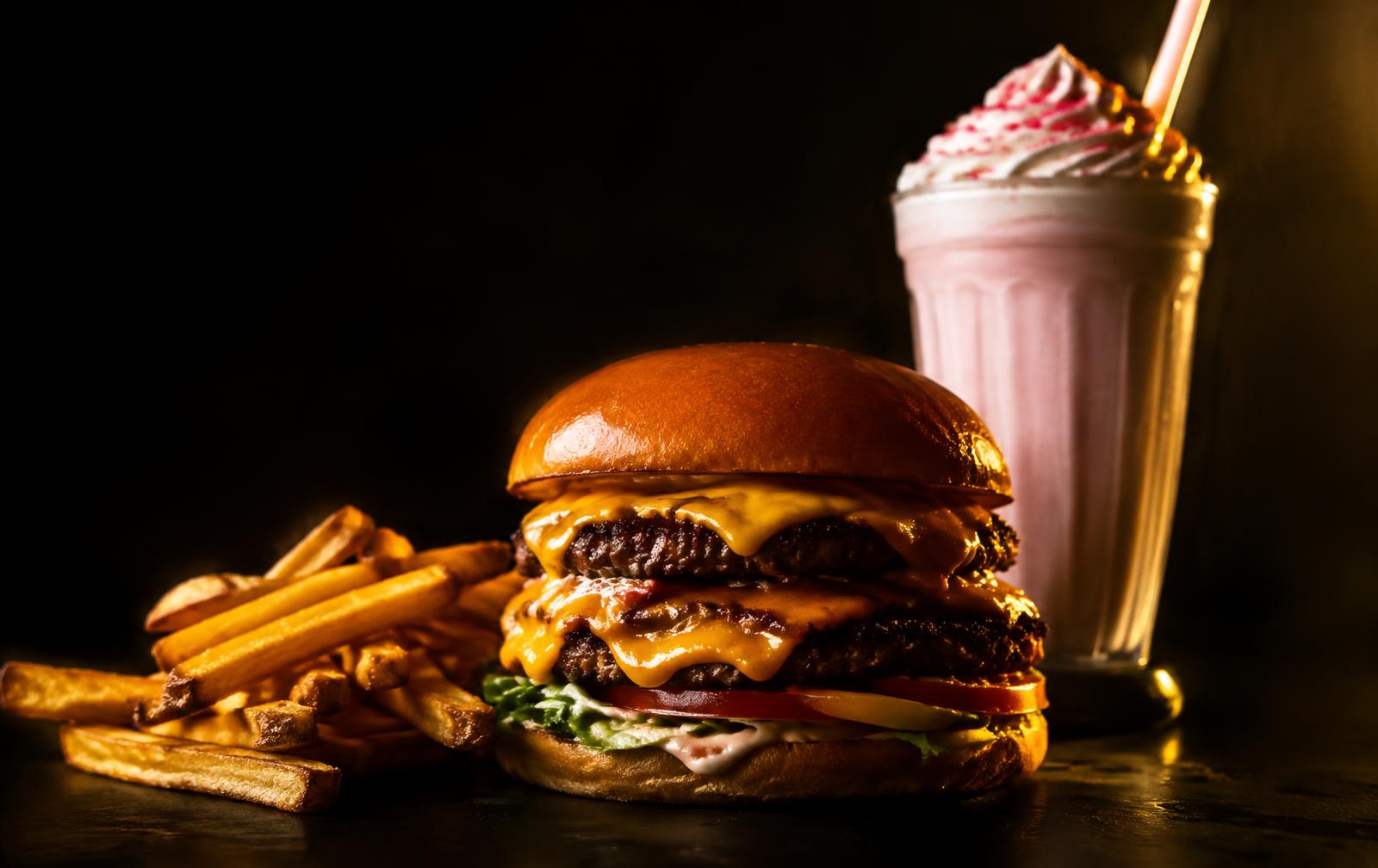 Burger, fries and a milkshake under warm studio lighting